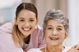 Caregiver embracing an older woman seated in a wheelchair