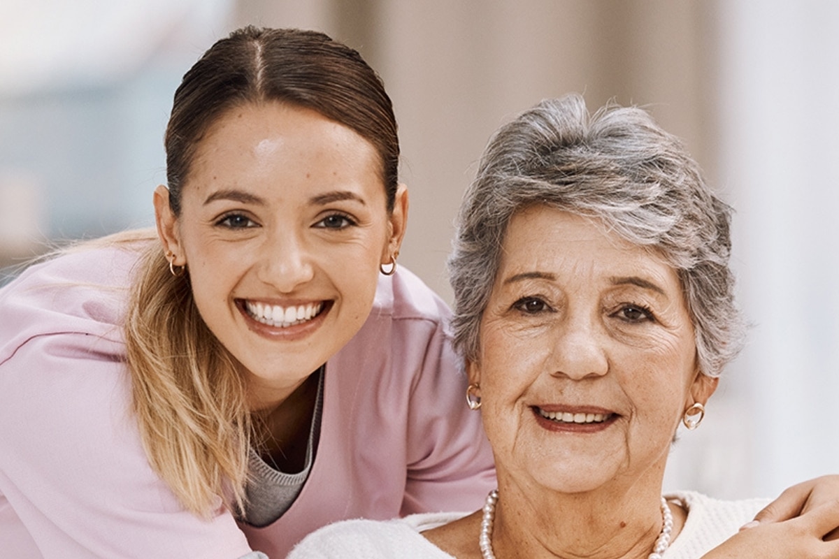 Caregiver embracing an older woman seated in a wheelchair
