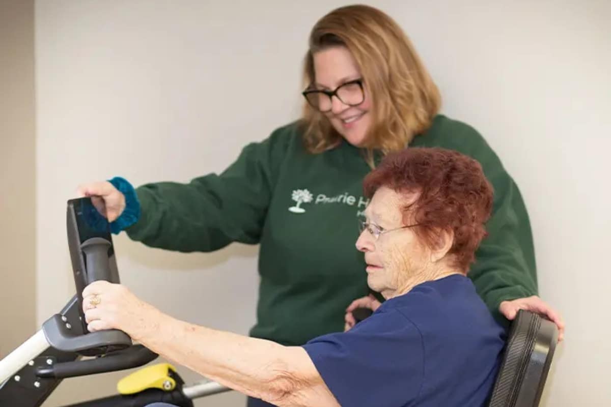 Care team member assisting an older woman in a wheelchair with a therapeutic activity