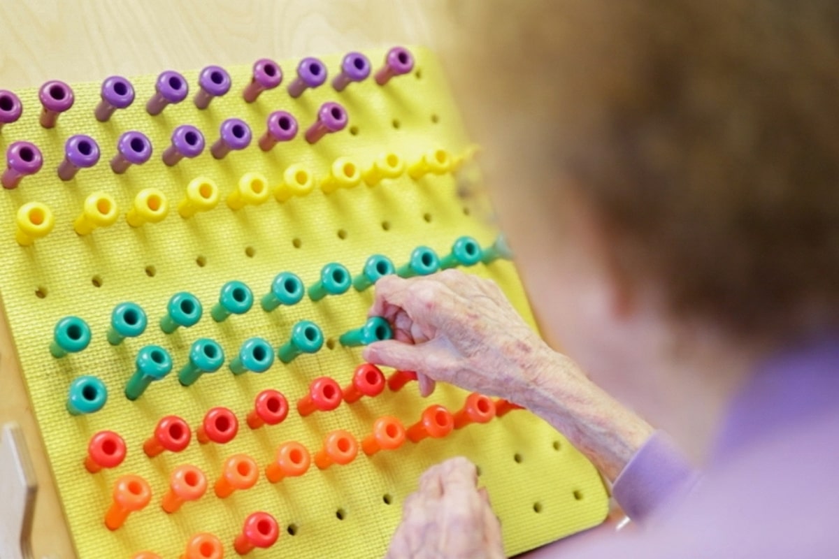 Older adult participating in a hands-on activity with colorful pegs